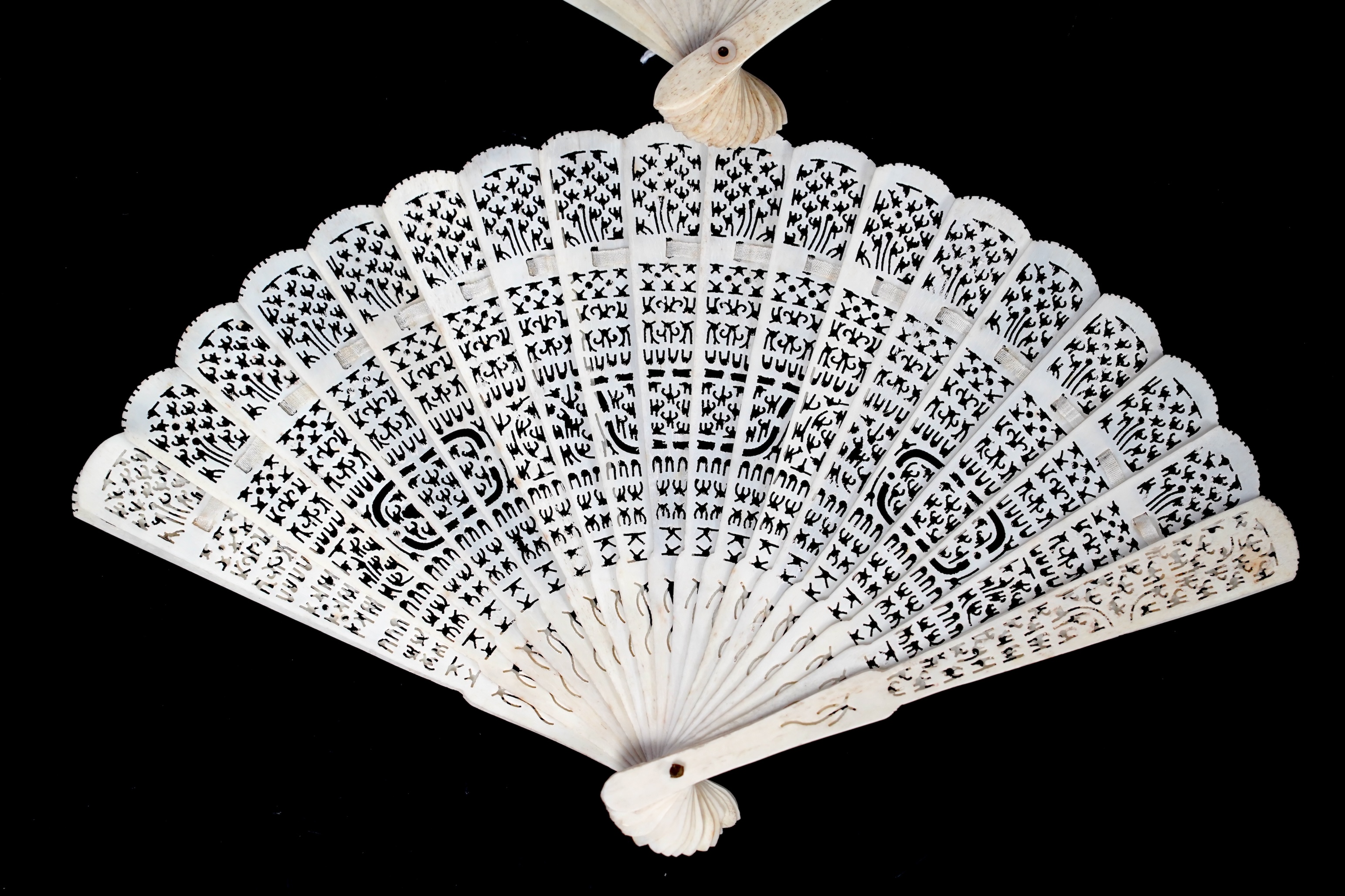 A mid 19th century Chinese brisé bone fan with intricate carving and a later smaller similar fan